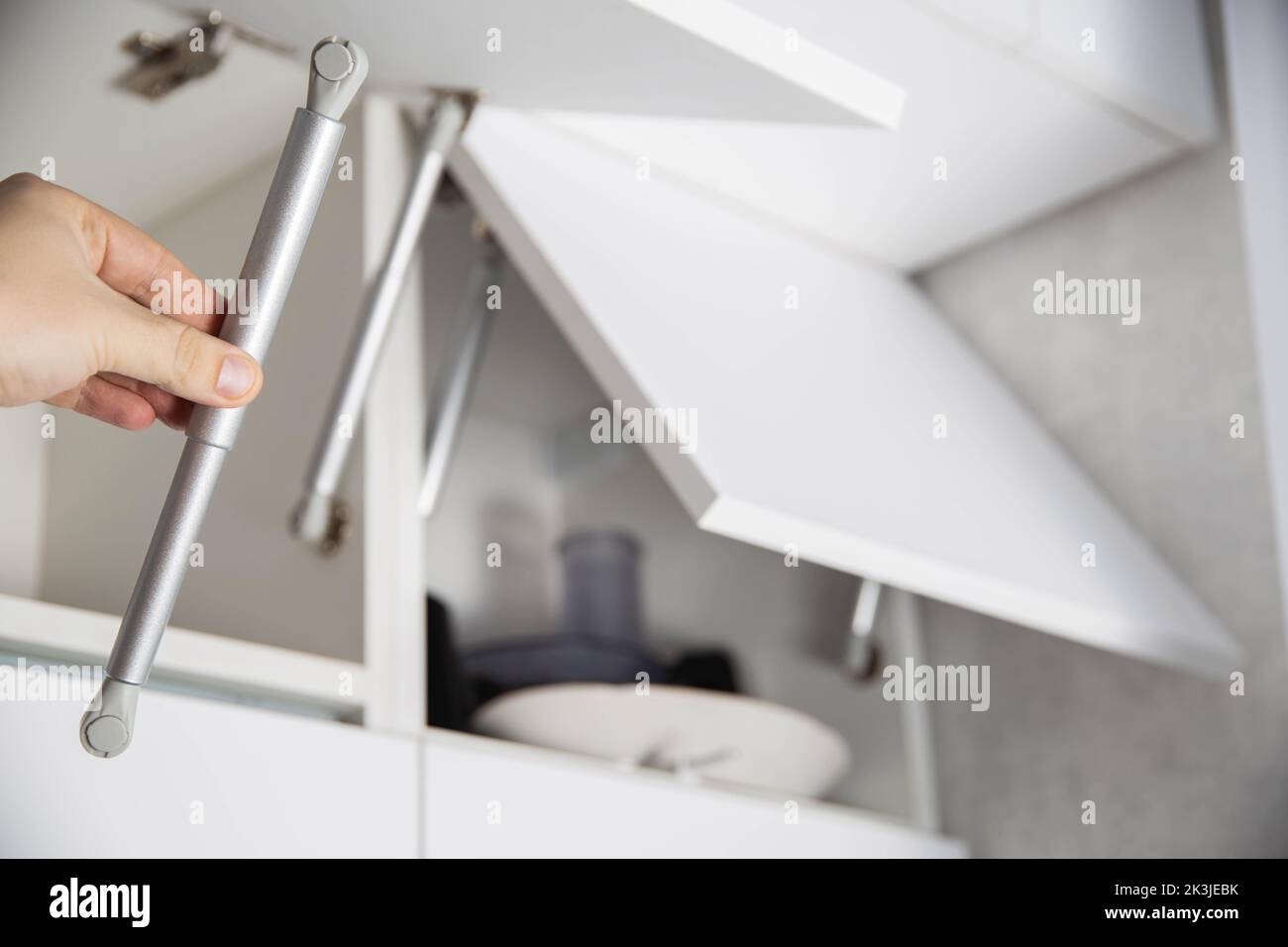 Ein Möbelmontagearbeiter hält eine einhole Gasfeder, um eine