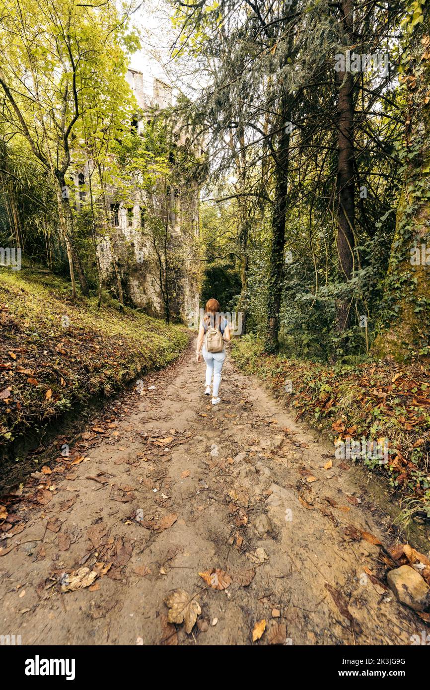 Vertikales Foto einer Frau, die auf einem von Bäumen umgebenen Pfad geht Stockfoto