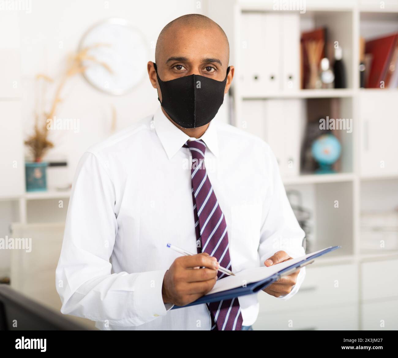 Porträt eines positiven Geschäftsmanns in Schutzmaske mit Dokumentenmappe Stockfoto