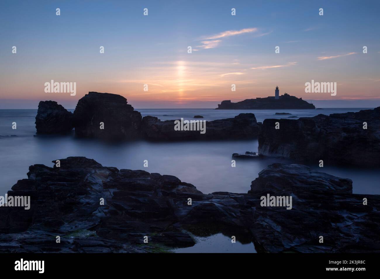 Langzeitaufnahme des verwackelten Leuchtturms cornwall bei Sonnenuntergang mit verschwommener Bewegung im Wasser Stockfoto