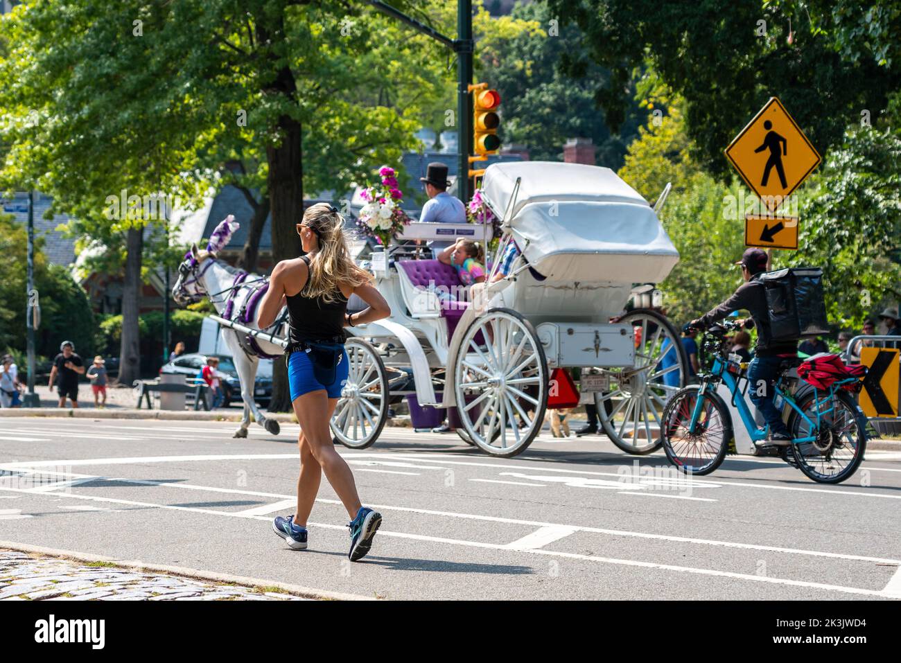 19.09.2020 Central Park New-York Girl joggt vor dem Hintergrund einer vorbeifahrenden Lustkutsche Stockfoto