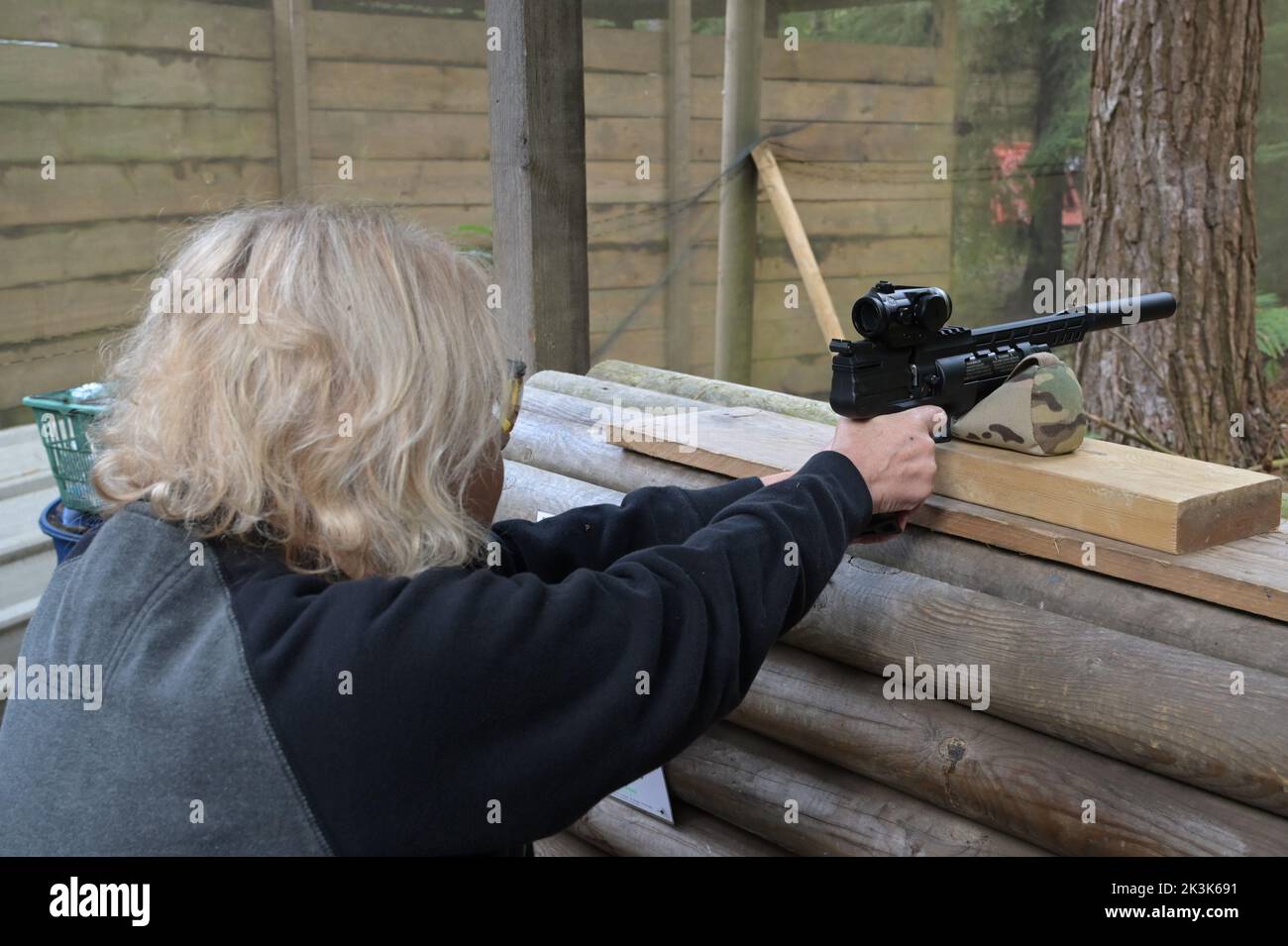 Eine deutsche Luftpistole HW44 pcp, die gerade von einer blonden Dame auf einen Schießstand abgefeuert wird. Stockfoto
