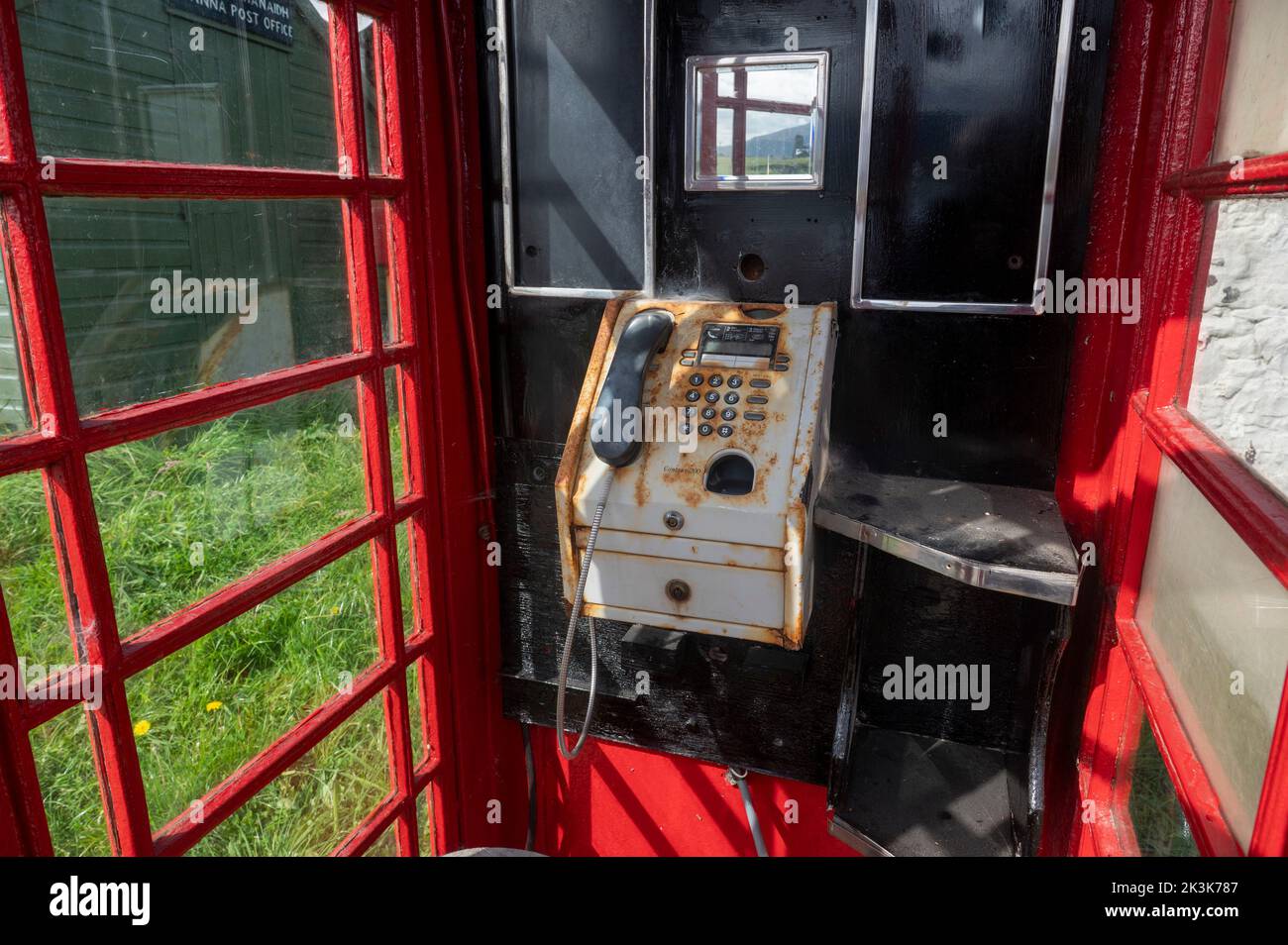 September 2022: Isle of Canna, Inner Hebrides, Schottland die alte rote Telefondose auf der Straße entlang der Küste Stockfoto