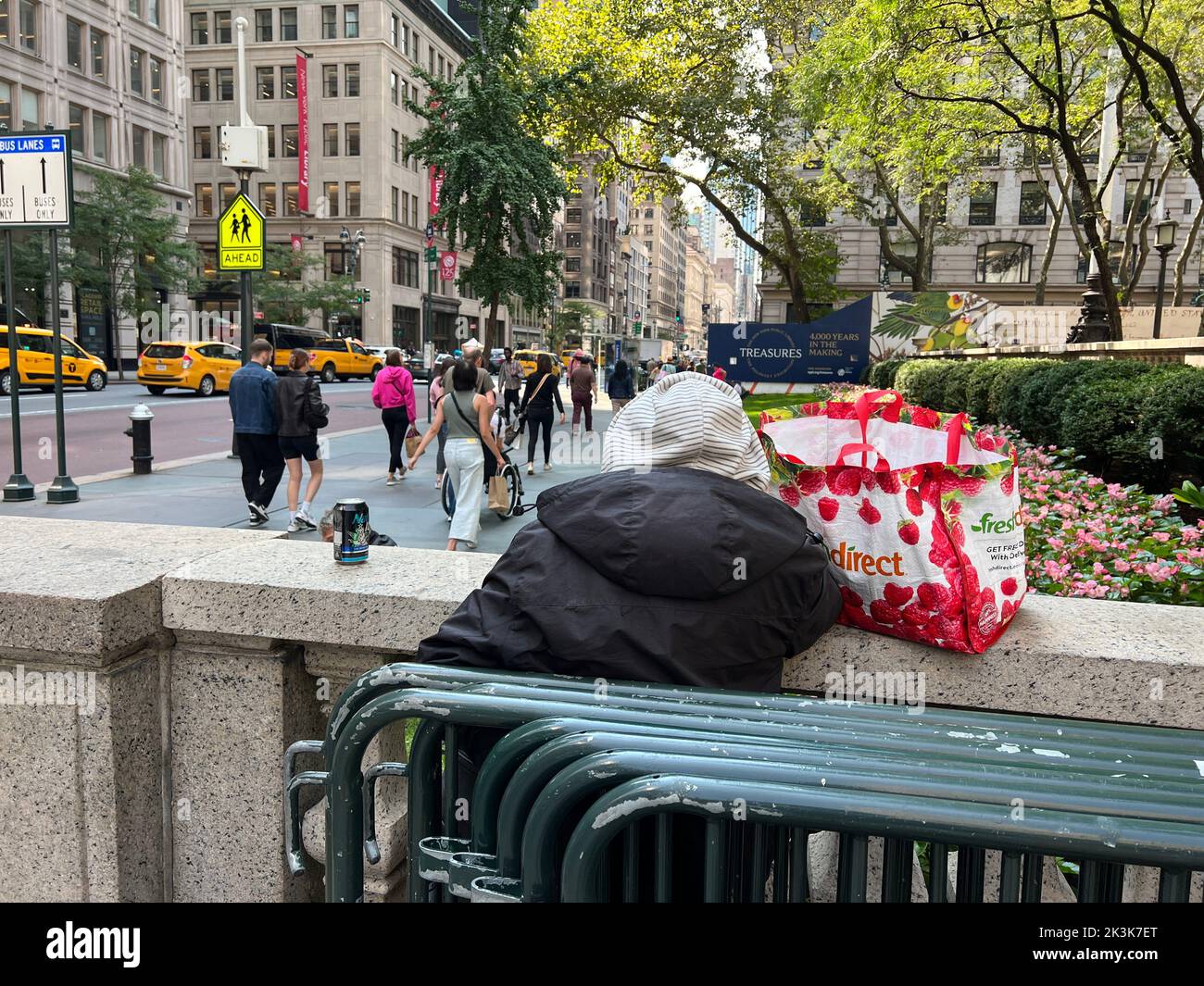 Obdachlose Frau blickt von der Terrasse der New York Public Library in der 42. Street auf die 5. Avenue. Stockfoto