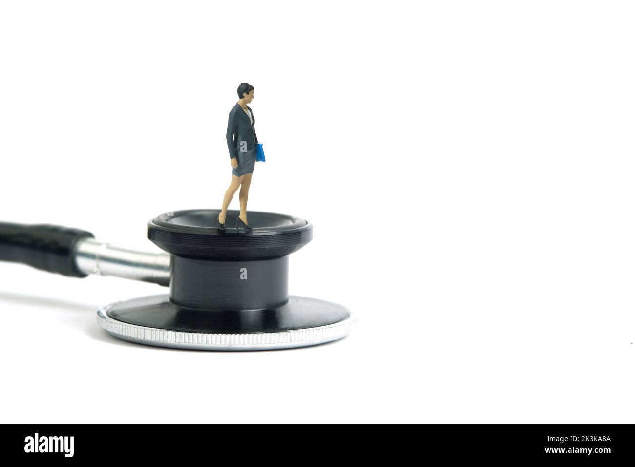 Miniatur Menschen Spielzeug Figur Fotografie. Konzept des medizinischen Check-up-Zeitplans. Eine Geschäftsfrau, die über dem Stethoskop steht. Isoliert auf weißem Hintergrund. I Stockfoto