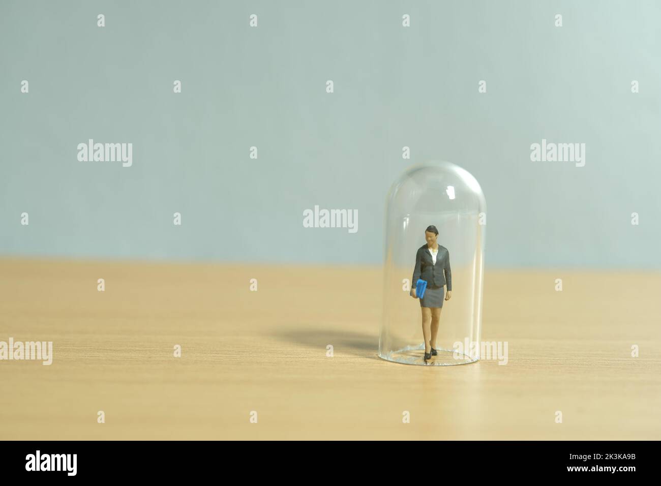 Miniatur Menschen Spielzeug Figur Fotografie. Frauenbeschränkung. Eine Geschäftsfrau, die in der Glaskuppel steht. Isoliert auf weißem Hintergrund. Bild pho Stockfoto