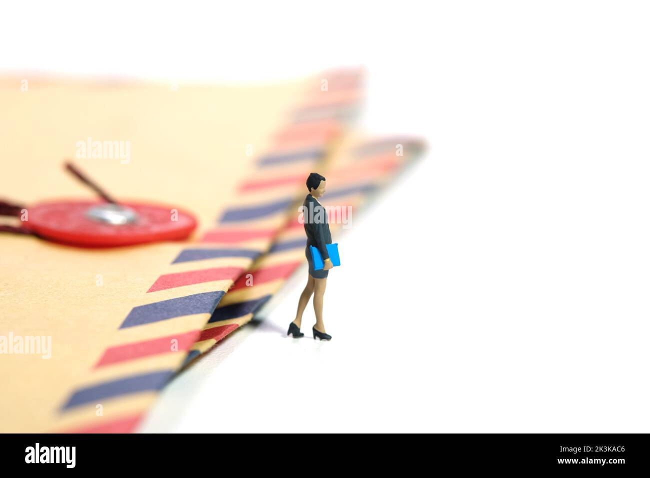 Miniatur Menschen Spielzeug Figur Fotografie. Eine Geschäftsfrau, die über dem Briefumschlag steht. Isoliert auf weißem Hintergrund. Bild phot Stockfoto