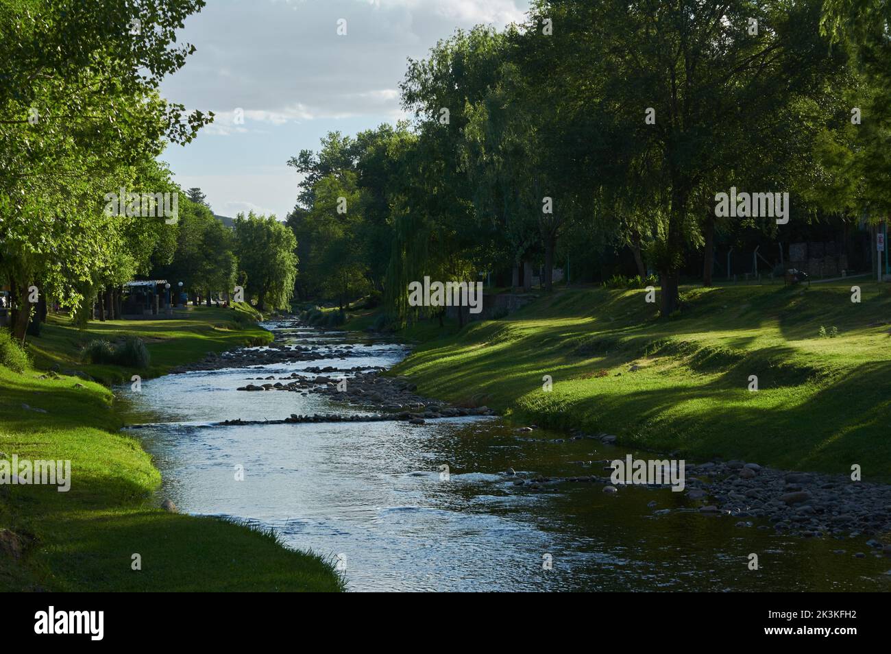 Eine schöne Aussicht auf einen Fluss in einem Park mit frischem Gras und grünen Bäumen Stockfoto