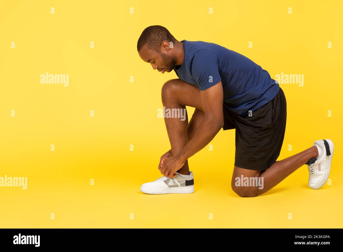 afroamerikanischer Sportler schnürte Schuhe auf gelbem Hintergrund Stockfoto