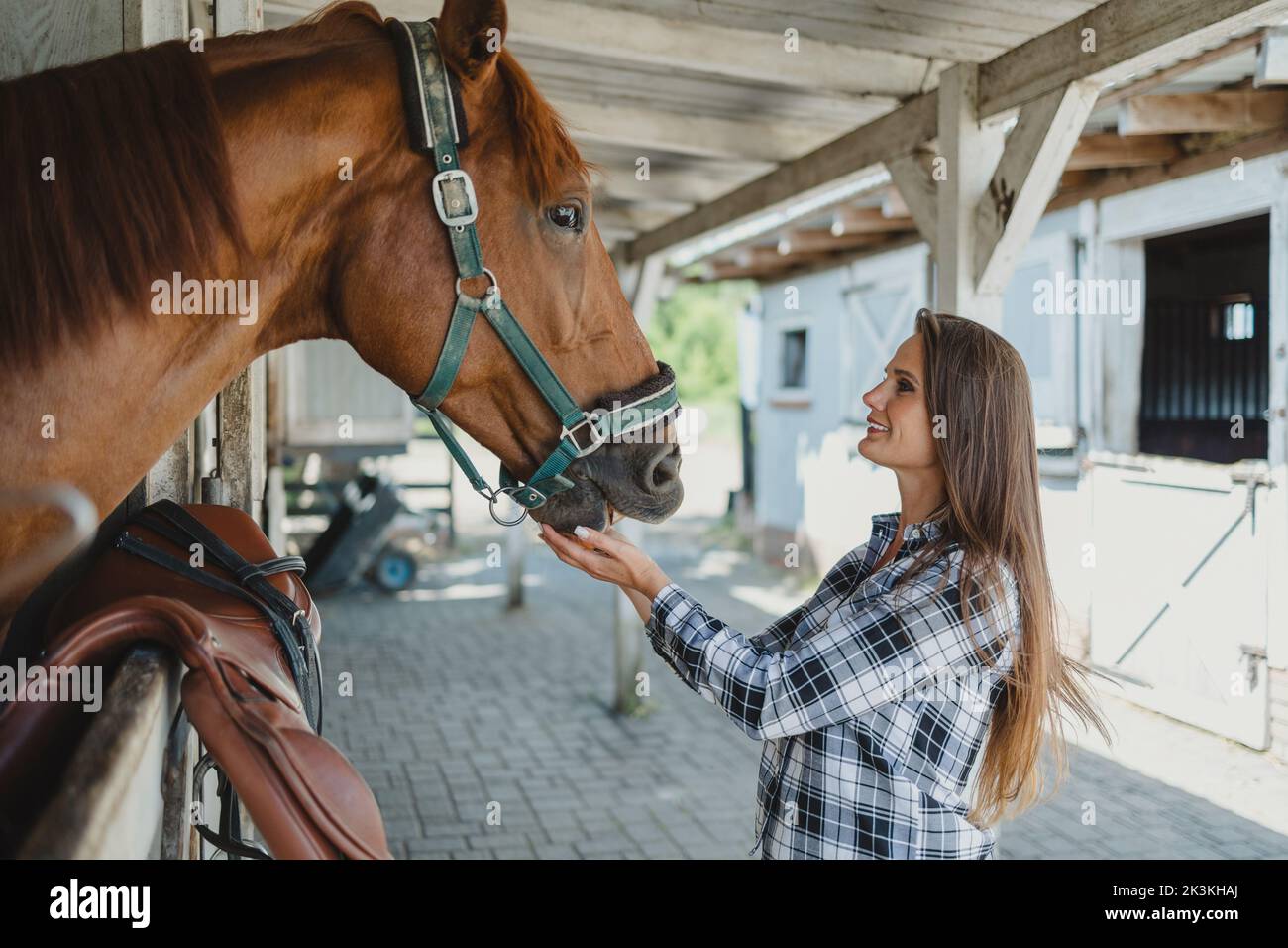 Junge Frau in einem Stall mit ihrem Pferd Stockfoto