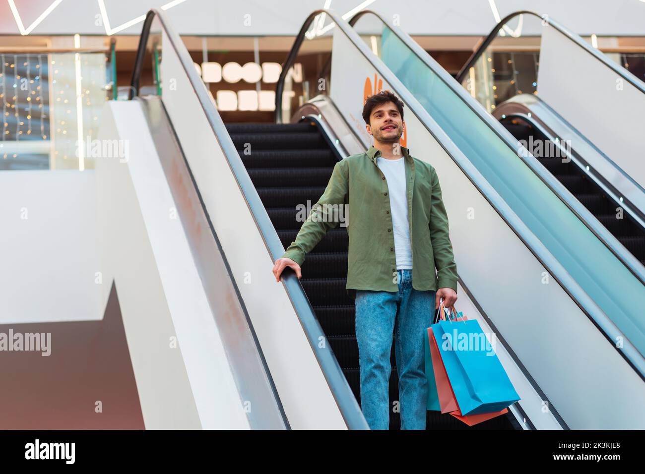 Mann Hält Einkaufstaschen Auf Beweglichen Treppen In Der Mall Stehen Stockfoto