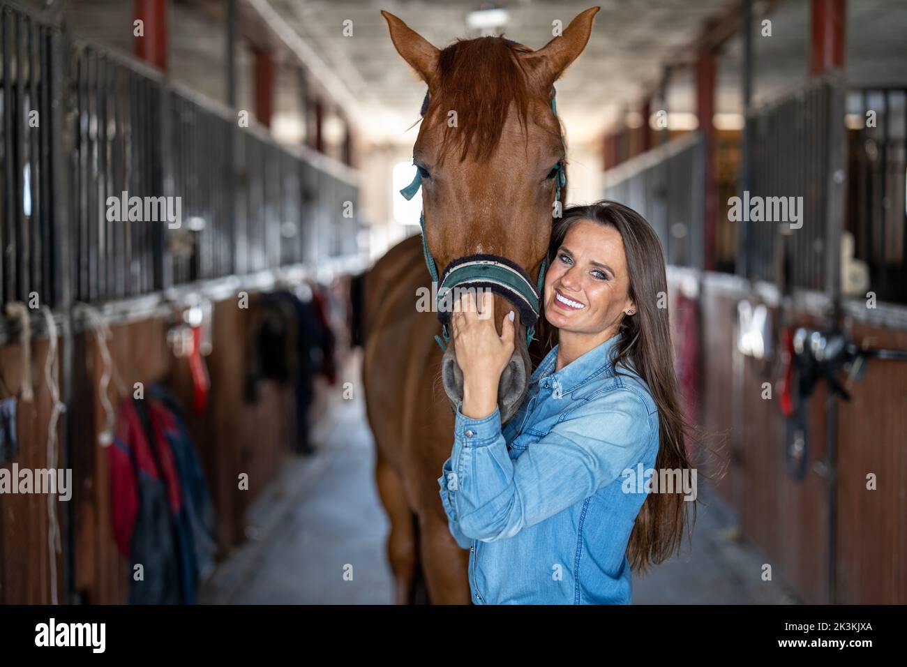 Junge Frau in einem Stall mit ihrem Pferd Stockfoto
