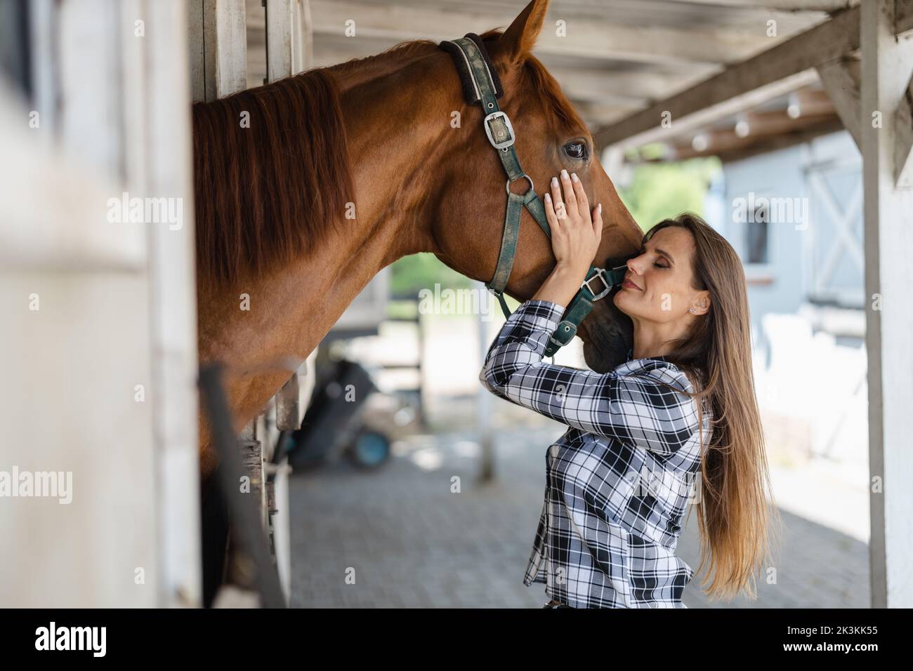 Junge Frau in einem Stall mit ihrem Pferd Stockfoto