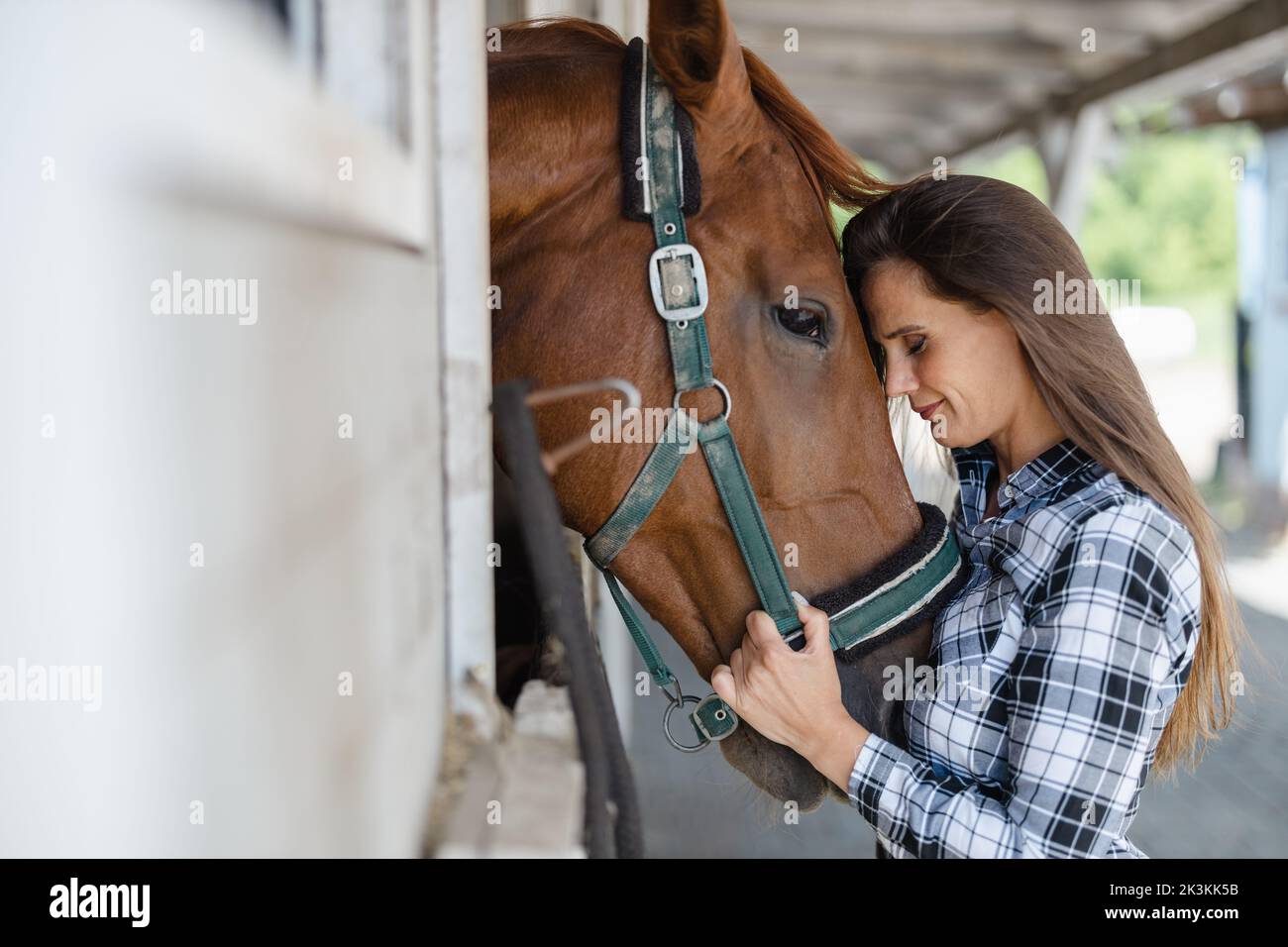 Junge Frau in einem Stall mit ihrem Pferd Stockfoto