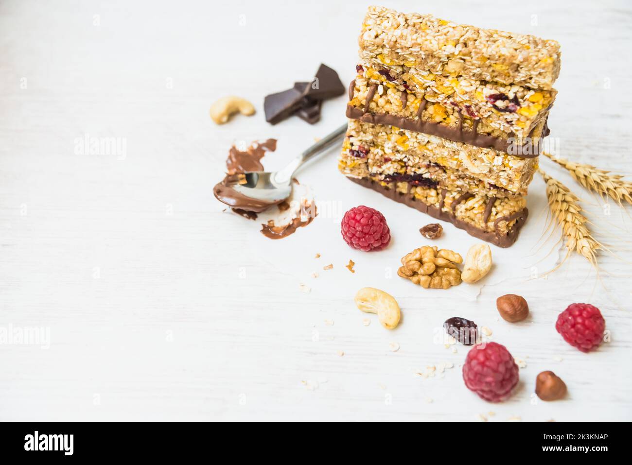 Ein Haufen verschiedener hausgemachter Müsliriegel mit Nüssen, Samen, dunkler Schokolade, Honig und Beeren auf weißem Hintergrund. Speicherplatz kopieren. Stockfoto