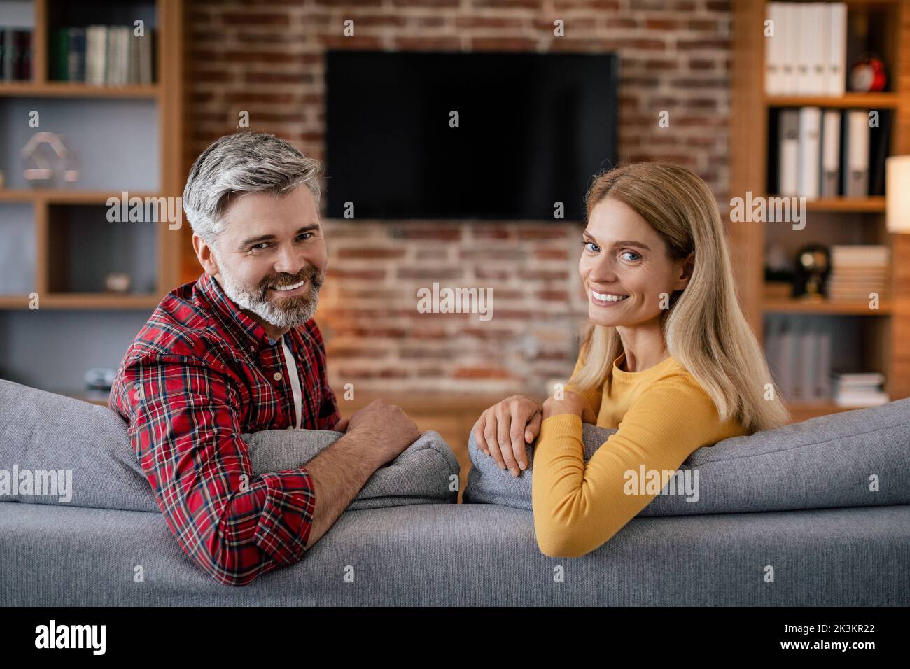 Ruhige lächelnde reife europäische Frau und Ehemann entspannen, genießen Sie Freizeit mit tv mit leerem Bildschirm Stockfoto