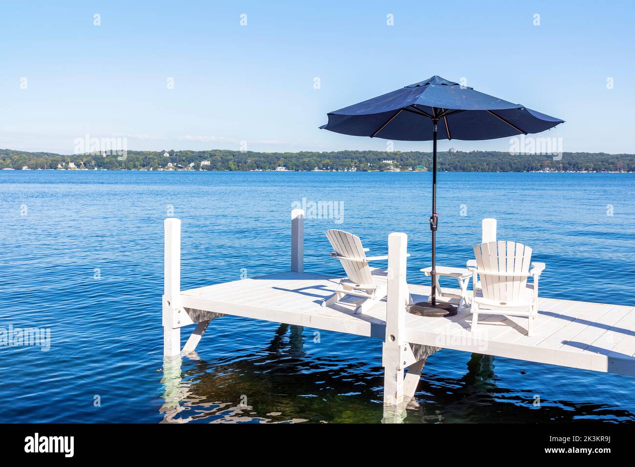 Weiße Holzliegen mit Sonnenschirm auf einem weißen Holzsteg, in der Nähe von Fontana, Genfersee, Wisconsin, Amerika Stockfoto