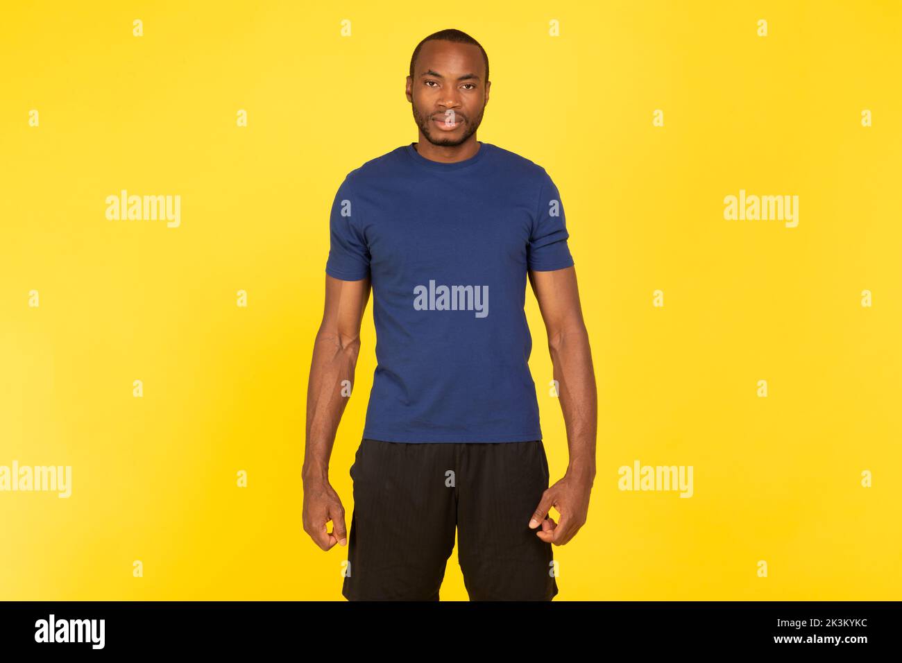 Motivierter Schwarzer Sportsman Schaut Auf Die Kamera, Die Auf Gelbem Hintergrund Steht Stockfoto