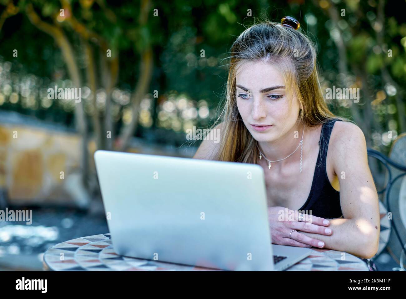 Porträt einer jungen kaukasischen Frau, die mit einem Laptop im Garten posiert und im Internet nach Informationen sucht. Lifestyle-Konzept. Stockfoto