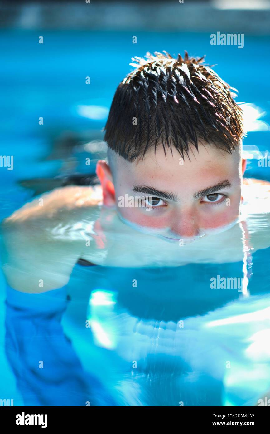 Porträt eines jungen kaukasischen Jungen in einem Schwimmbad, bis zu seiner Nase in Wasser getaucht. Lifestyle-Konzept. Stockfoto