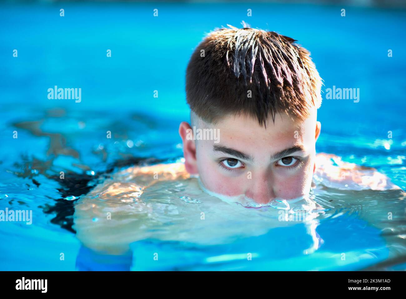 Porträt eines jungen kaukasischen Jungen in einem Schwimmbad, bis zu seiner Nase in Wasser getaucht. Lifestyle-Konzept. Stockfoto