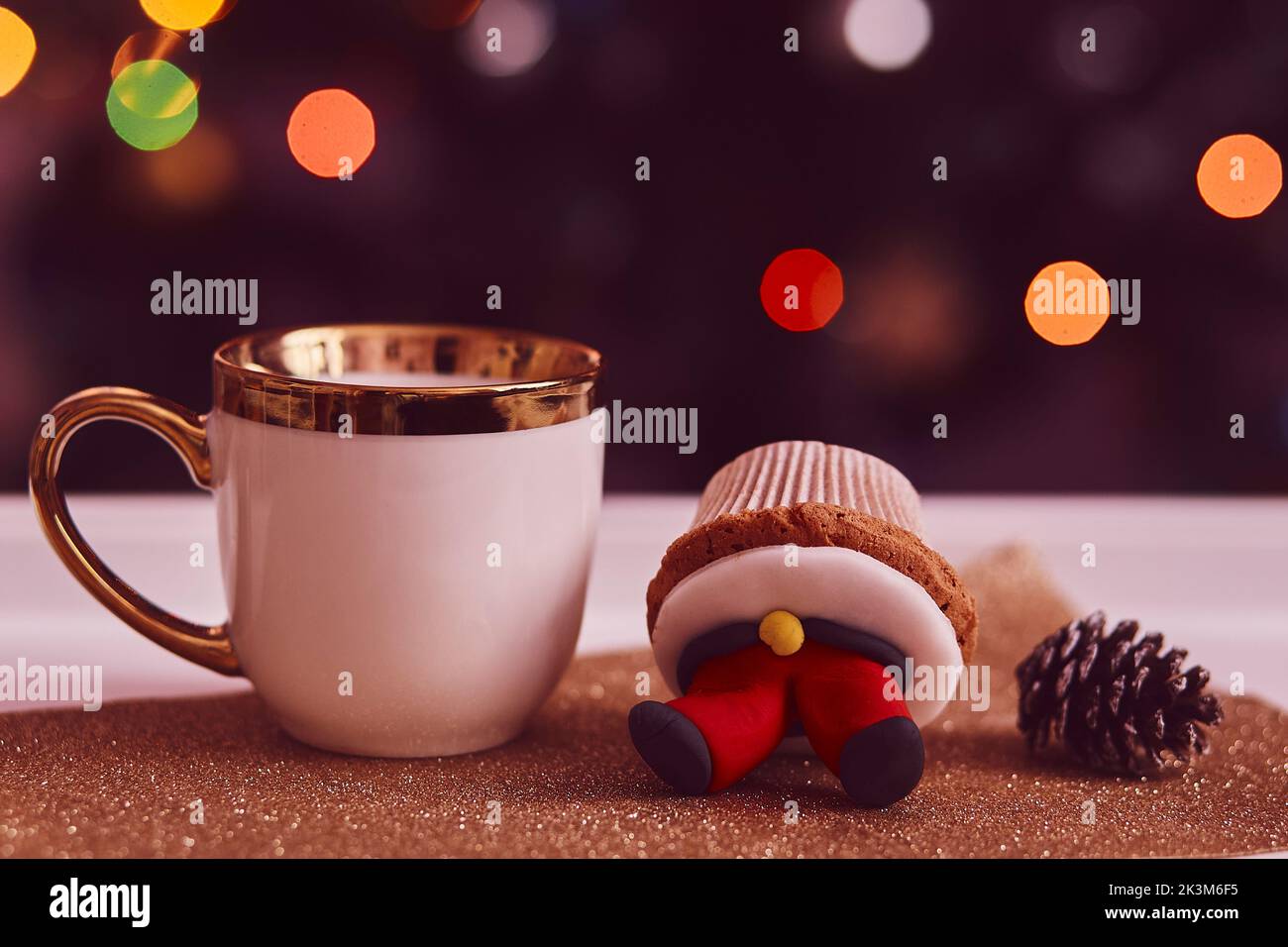 Gemütliche Weihnachtszeit. Dekorative Cupcakes und eine Tasse Tee vor dem Weihnachtsbaum. Gute Laune, festliche Stimmung. Selektiver Fokus Stockfoto