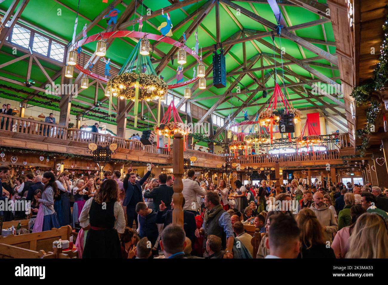 Menschen sitzen im Bierzelt auf dem Oktoberfest München. Fröhliche Menschen beim Biertrinken beim weltberühmten Volksfest feiern und zu bayerischer Musik tanzen Stockfoto