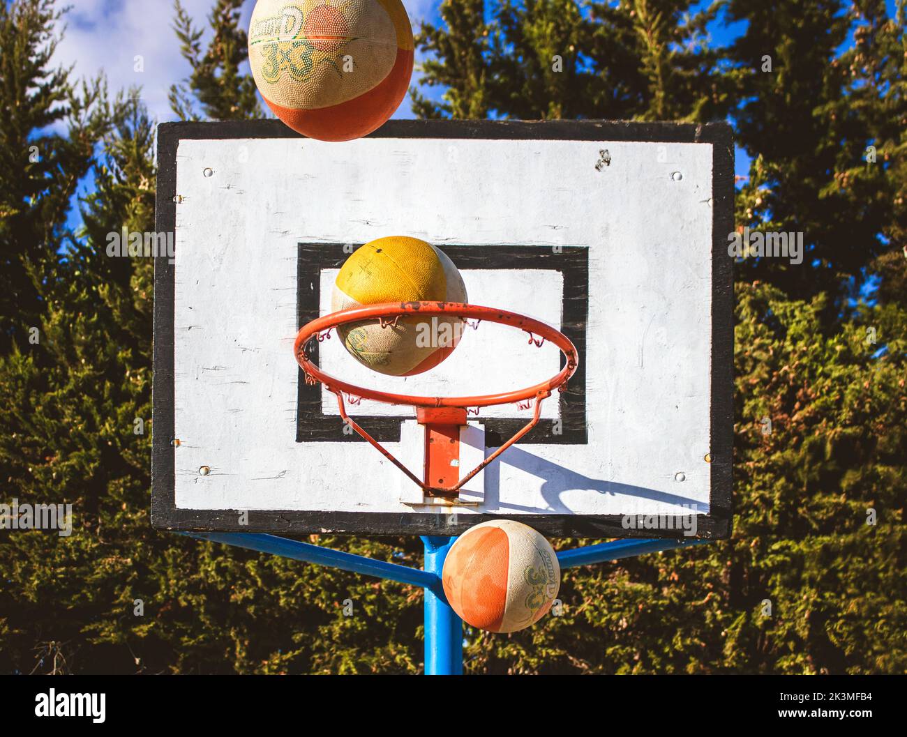 Drei Basketballkörbe treffen gleichzeitig in einem Korb auf einem städtischen Sportplatz im Freien Stockfoto