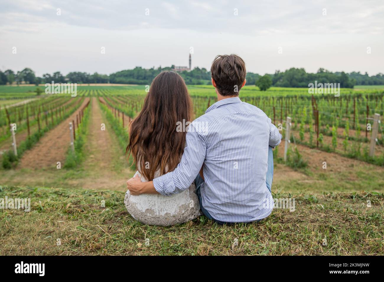 Zurück Porträt ein verliebtes junges Paar sitzt im Frühling im Weinberg und blickt auf den Horizont. Stockfoto