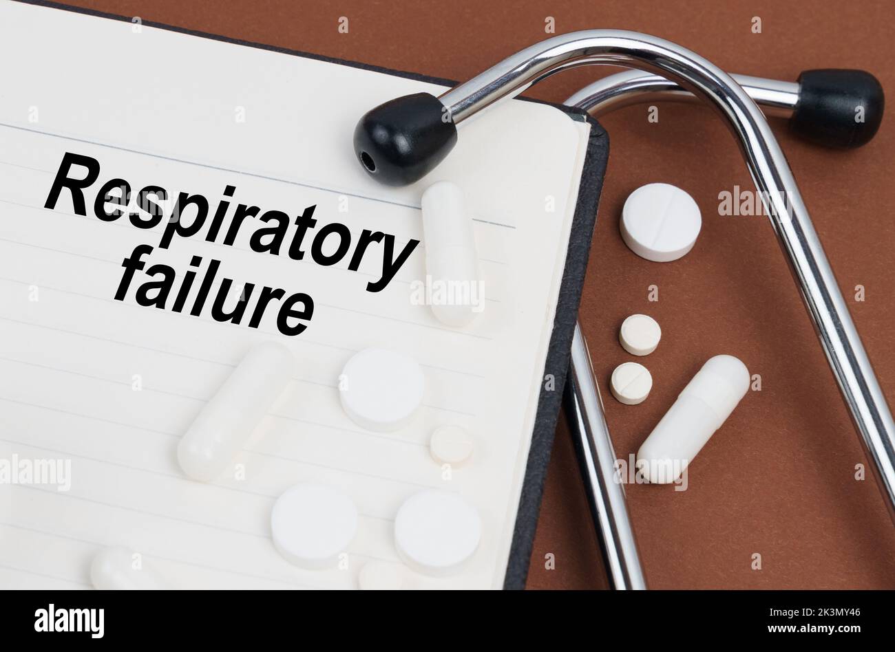 Medizinisches Konzept. Auf einer braunen Oberfläche liegt ein Stethoskop, Pillen und ein Notizblock mit der Aufschrift - Atemversagen Stockfoto
