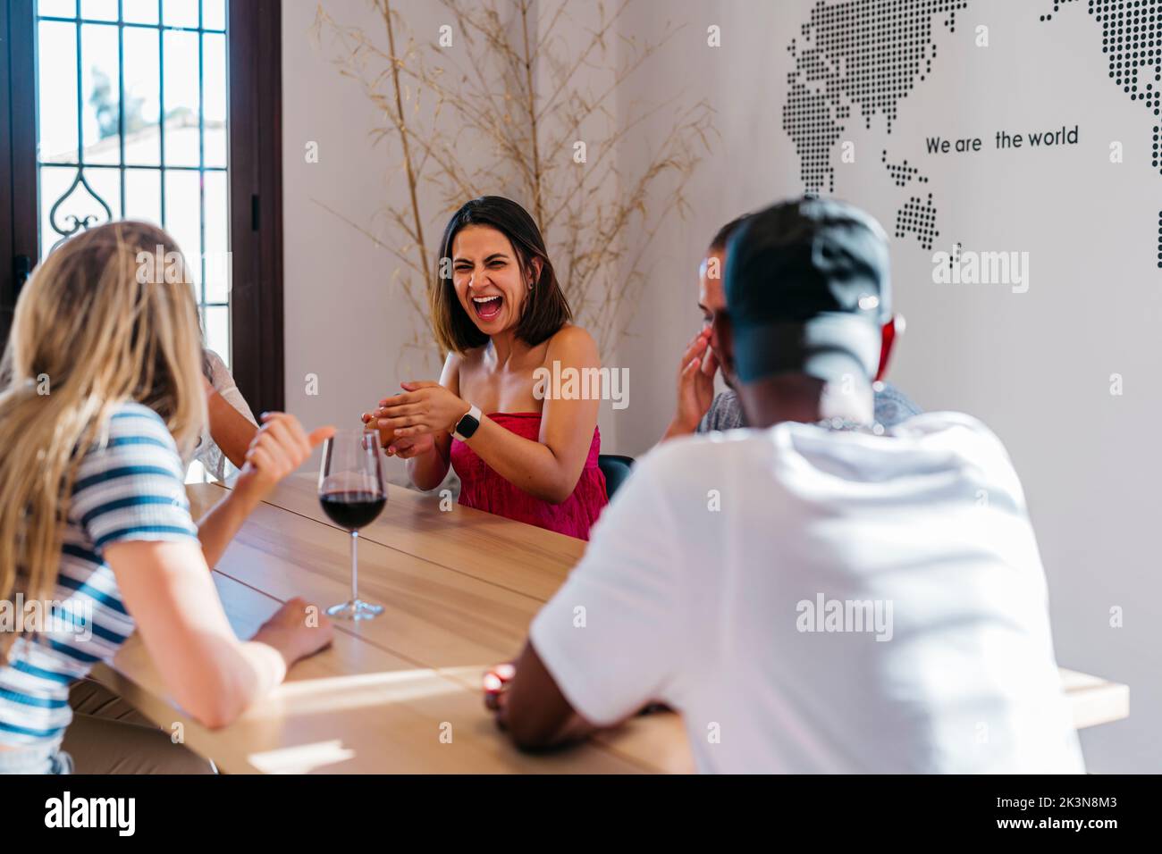 Die junge lateinerin lacht laut, während sie mit Freunden würfelt Stockfoto