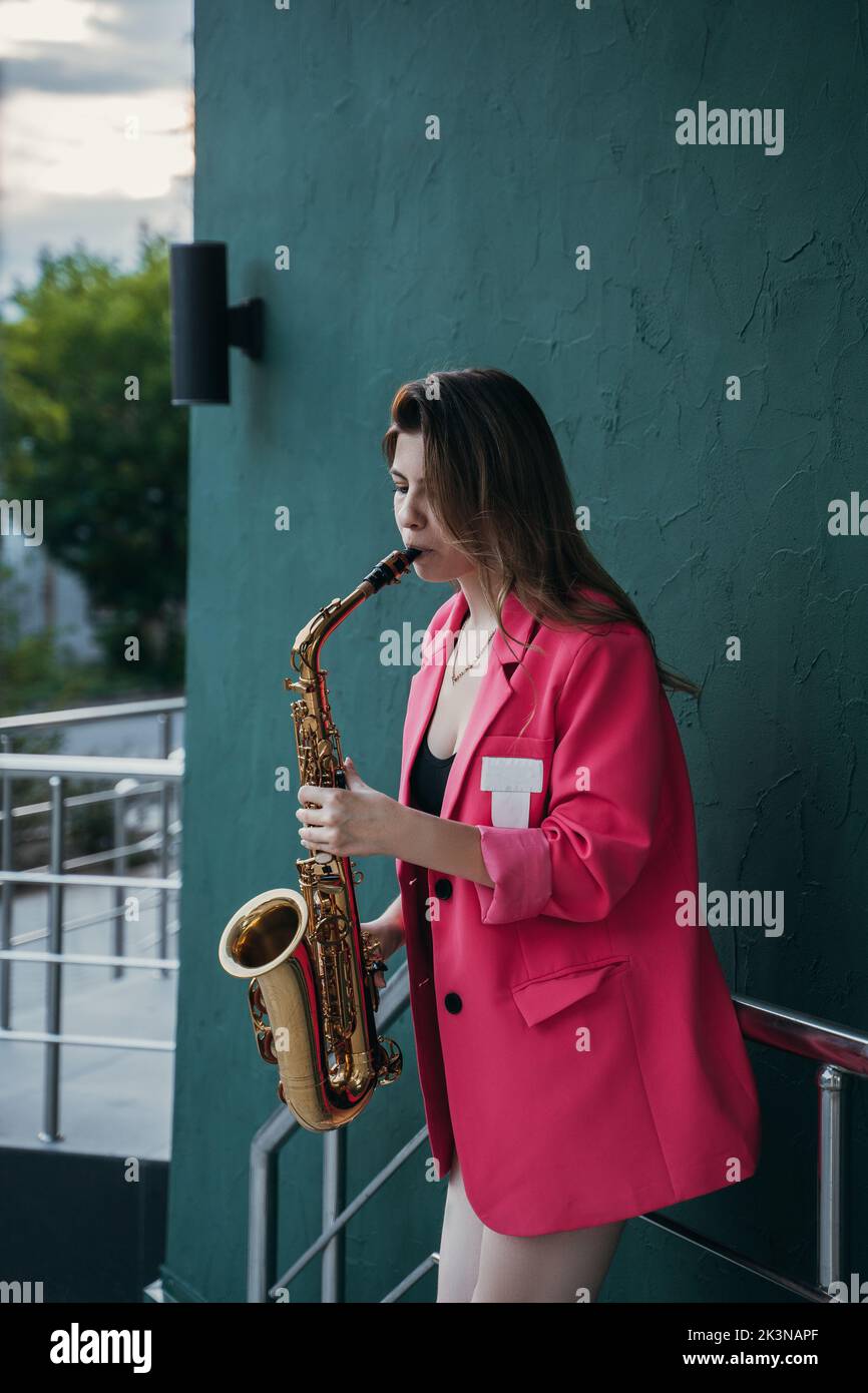Junges Mädchen spielt Saxophon auf der Straße der Stadt Stockfoto