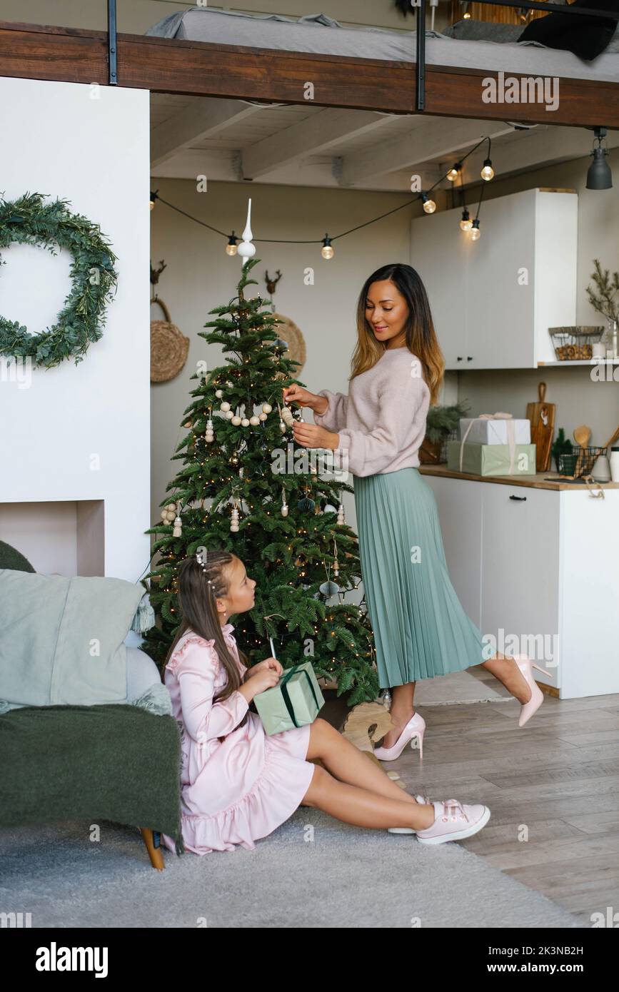 Mutter und Tochter dekorieren den Weihnachtsbaum und packen Geschenke Stockfoto