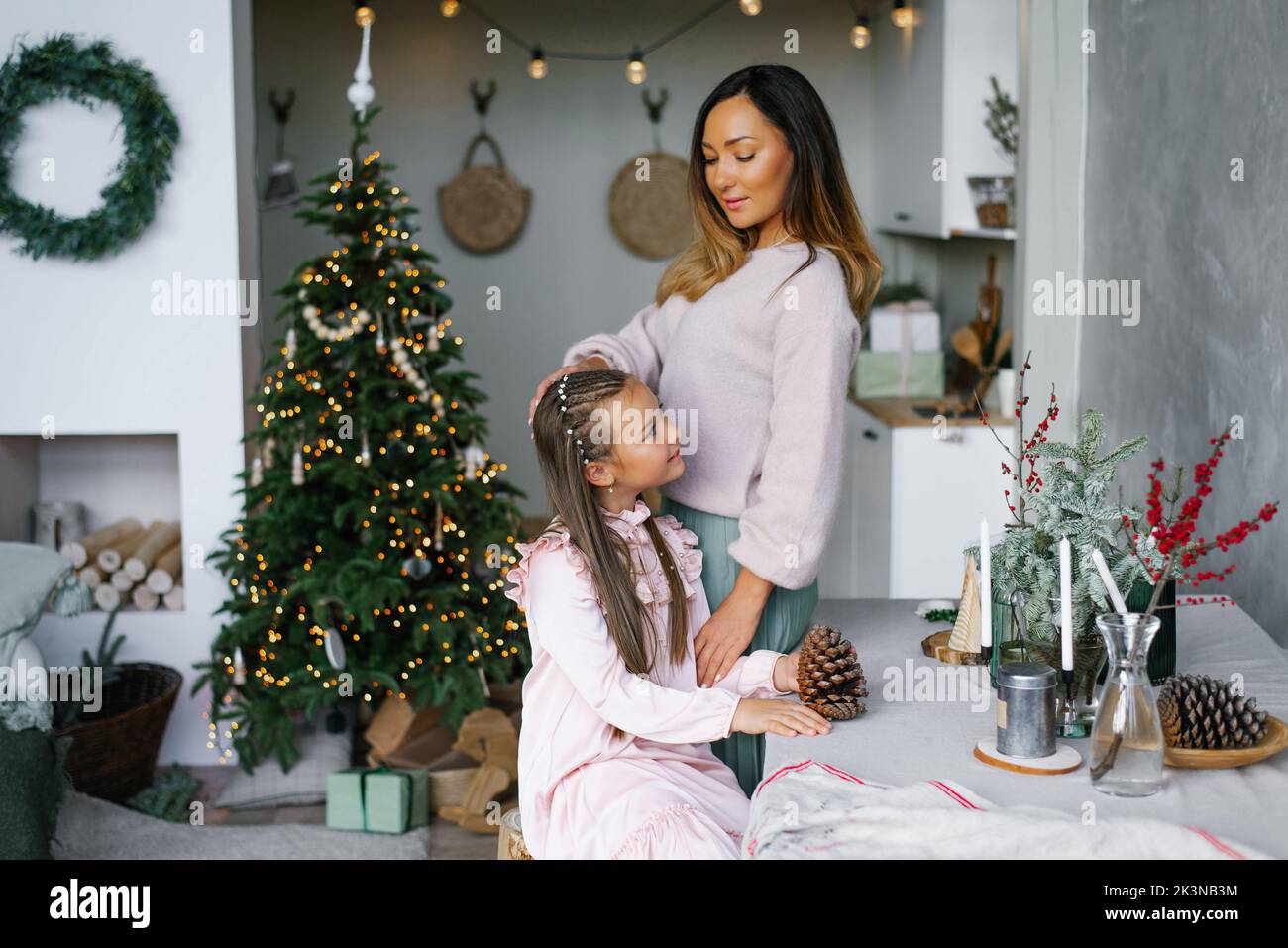 Mädchen sitzt an einem Tisch im Wohnzimmer, das zu Weihnachten geschmückt ist Stockfoto
