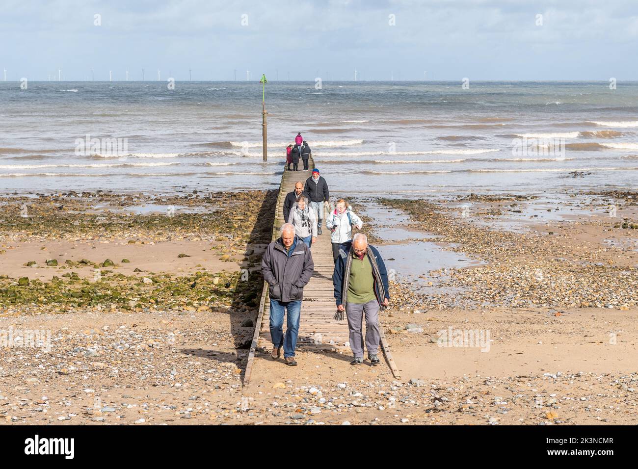 Leute, die auf einem Steg am Strand in Llandudno, Nordwales, Großbritannien, spazieren gehen. Stockfoto