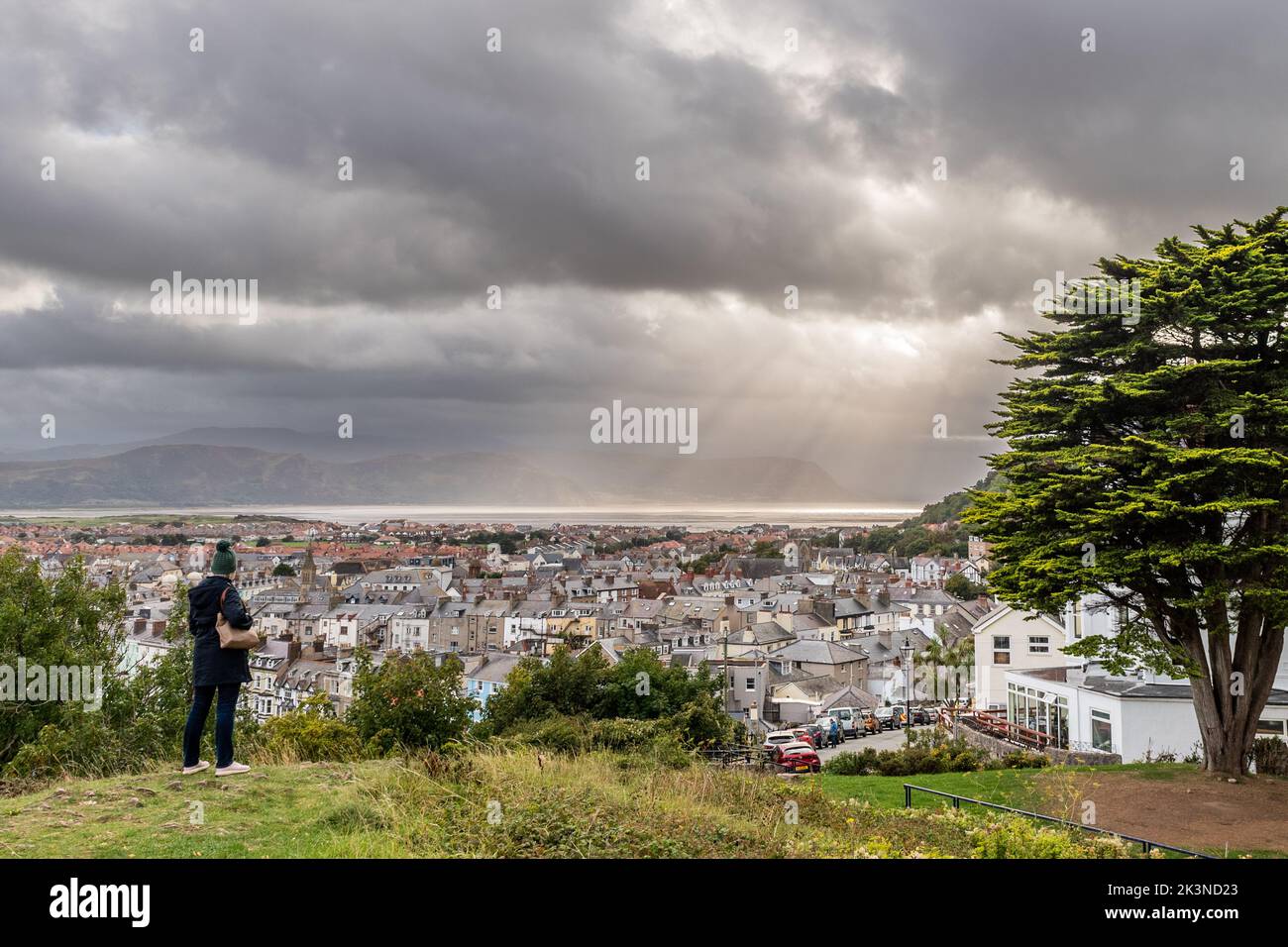 Frau, die aus Happy Valley, Llandudno, North Wales, Großbritannien, den dramatischen Himmel über der Stadt Llandudno betrachtet. Stockfoto