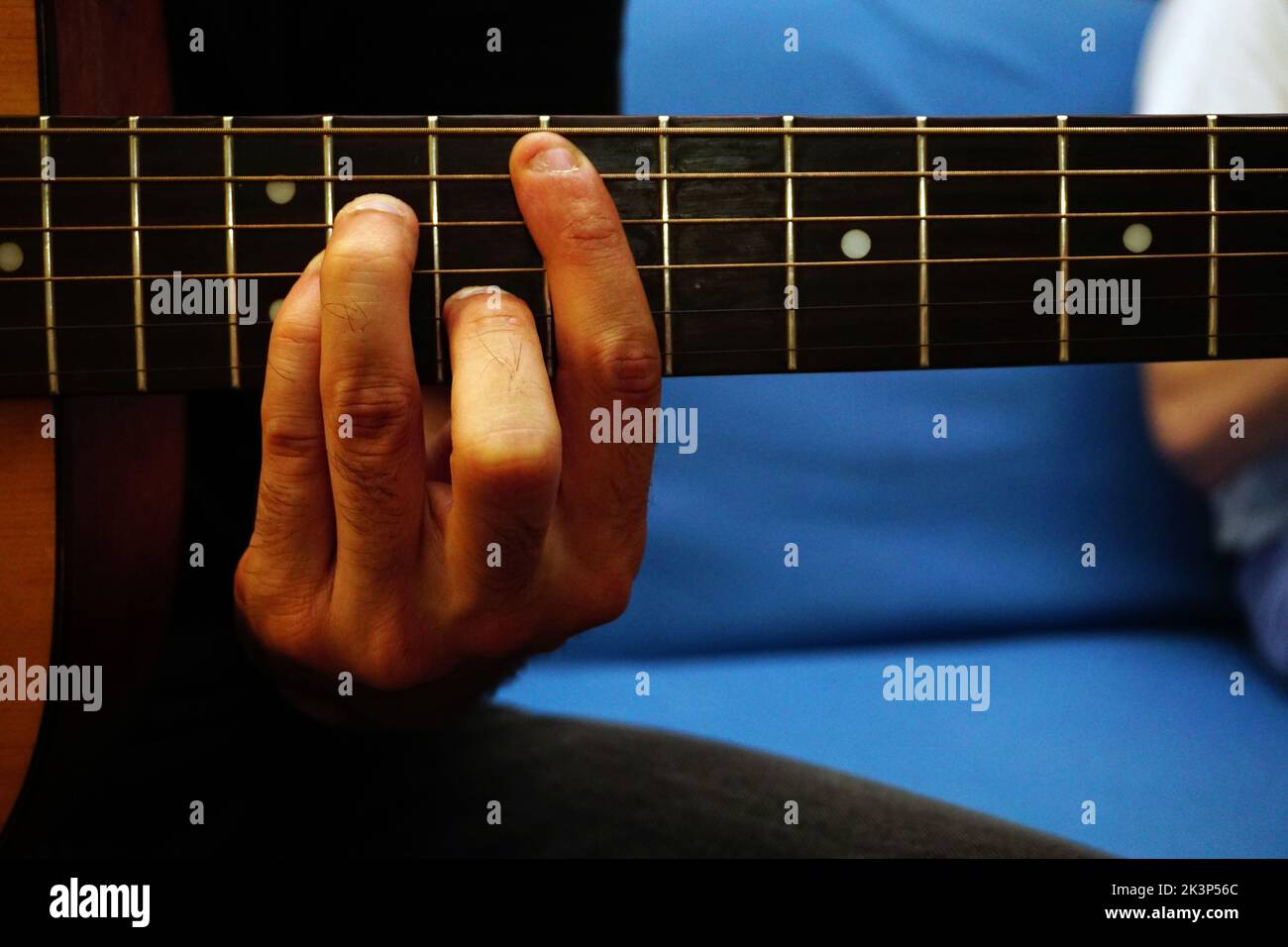 Eine Nahaufnahme eines Mannes, der Gitarre spielt und einen Barre-Akkord hält Stockfoto