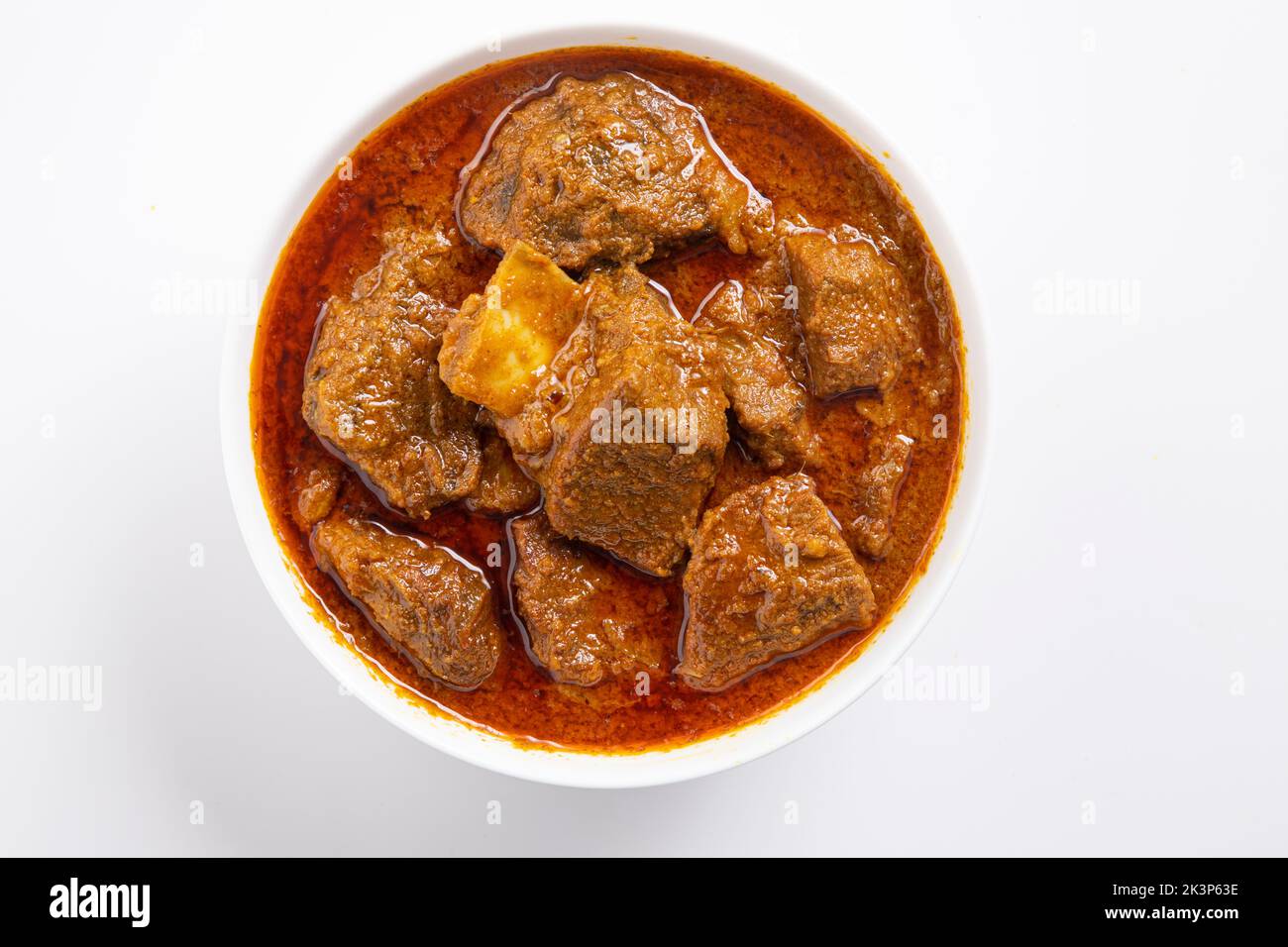 Rind-Masala oder Braten, kerala-Stil hausgemachtes Rezept garniert mit Kokosnussstücken und Kerrgeblättern, die in weißen B-Eule mit weißem Backgroun angeordnet ist Stockfoto