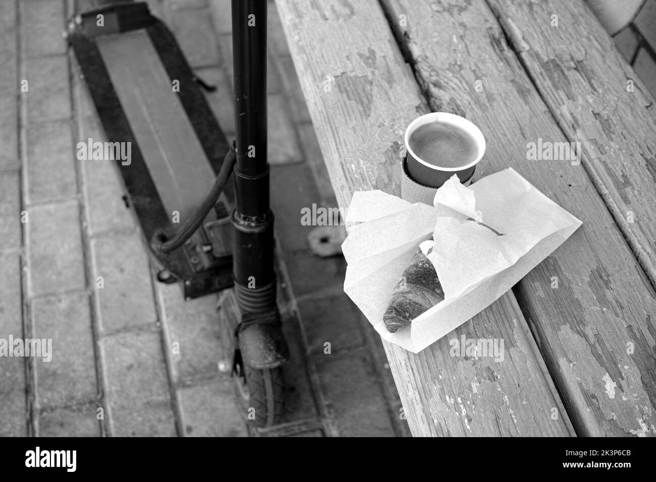 Outtdor schoss schwarz-weiß ein Croissant, Kaffee und einen Roller Stockfoto