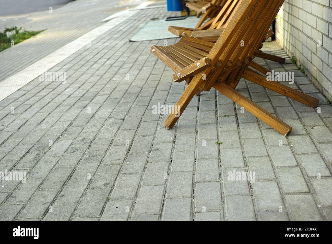 Gemütliche Sessel aus Holz, die außerhalb des Hauses auf gefliestem Boden aufgestellt sind Stockfoto