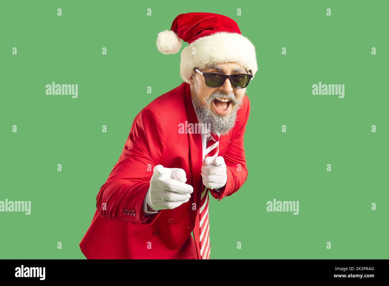 Fröhlicher lustiger Mann in rotem Anzug, Weihnachtshut und cooler Sonnenbrille zeigt mit dem Finger auf dich Stockfoto