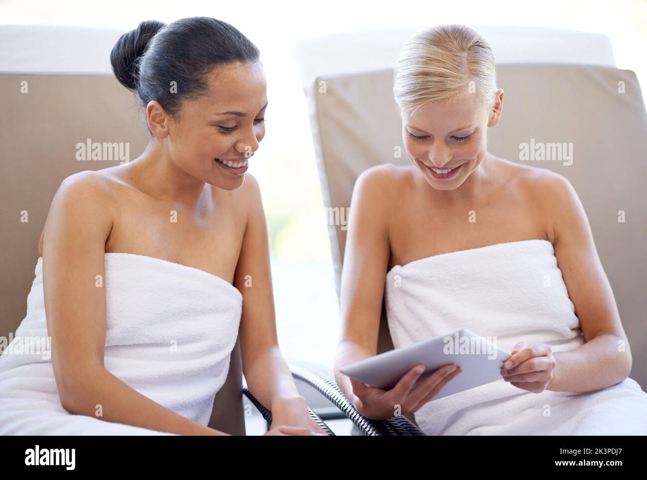 Zwei junge Frauen schauen sich ein Magazin in einem Beauty Spa an. Stockfoto