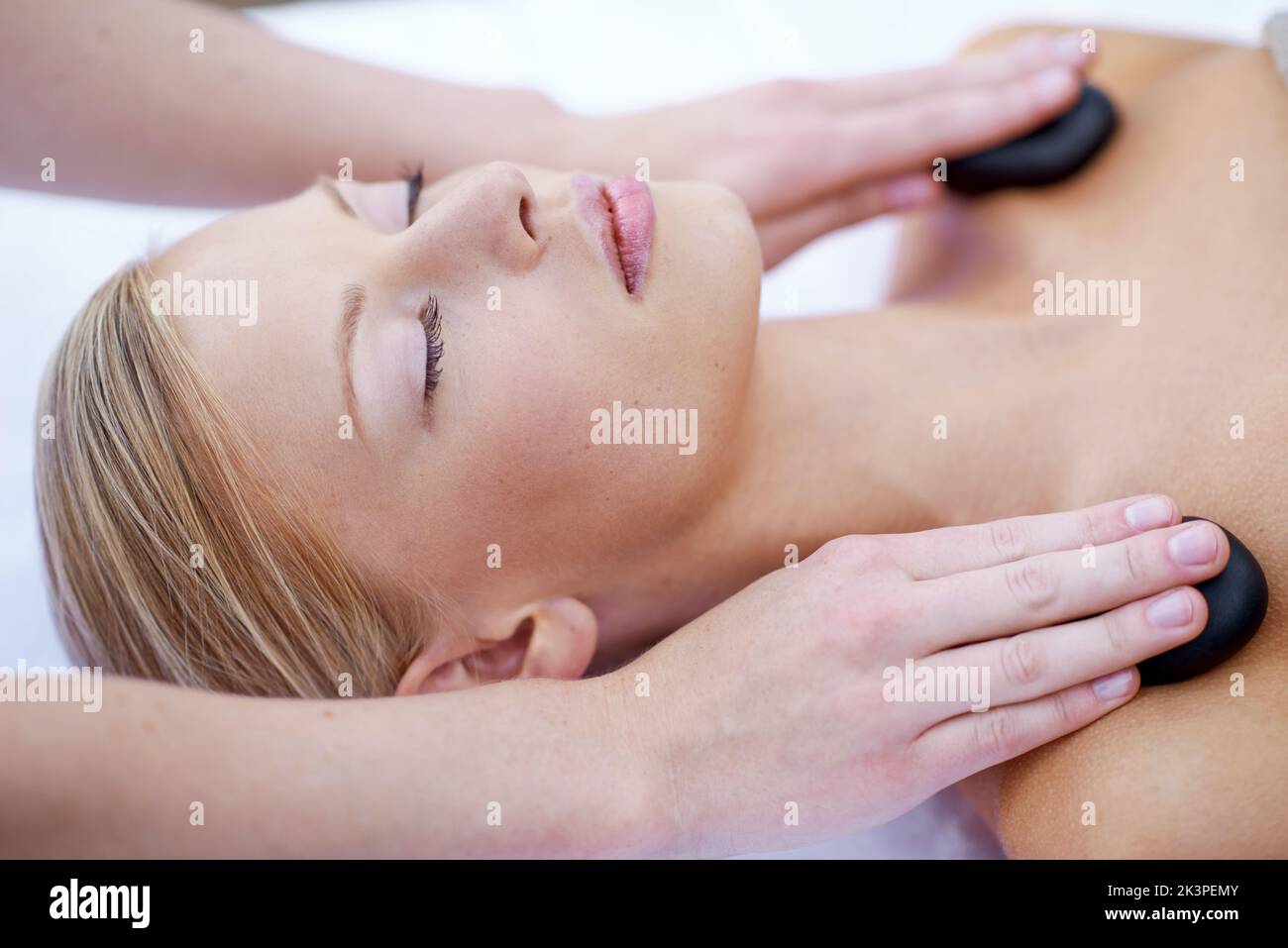 Genießen Sie eine Hot Stone Massage mit einem Freund. Eine junge Frau, die auf einem Massageliegen liegt. Stockfoto