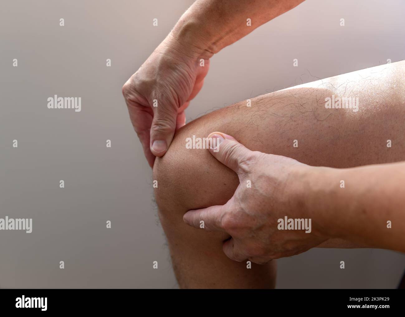 Eine Person mit Knieschmerzen massiert es zur Erleichterung. Verletzungen. Arthritis. Stockfoto