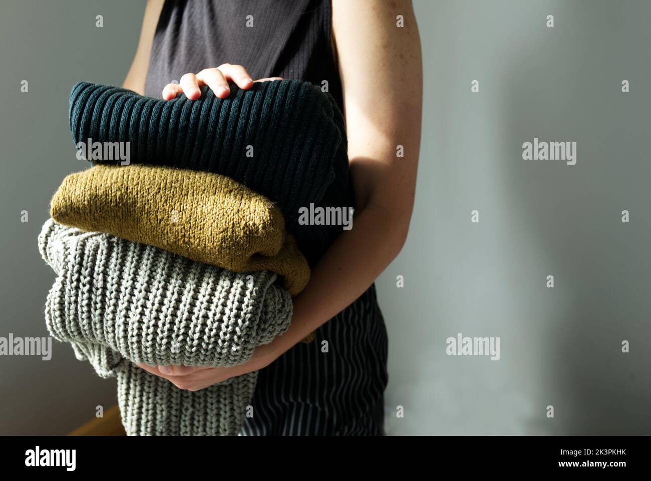 Frau hält in ihrem Handstapel warme Wollpullover und Strickjacken Stockfoto