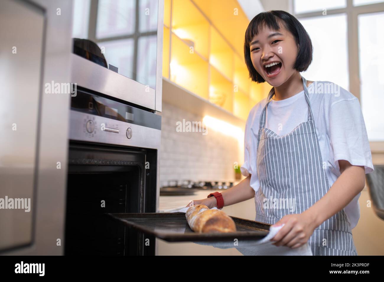 Glückliche junge Hausfrau, die in der Küche einen Kuchen backt Stockfoto