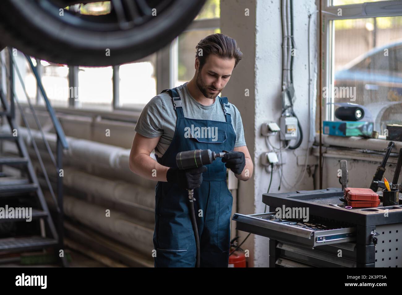 Fokussierter Autotechniker, der die Bohrmaschine in seiner Werkstatt verwendet Stockfoto