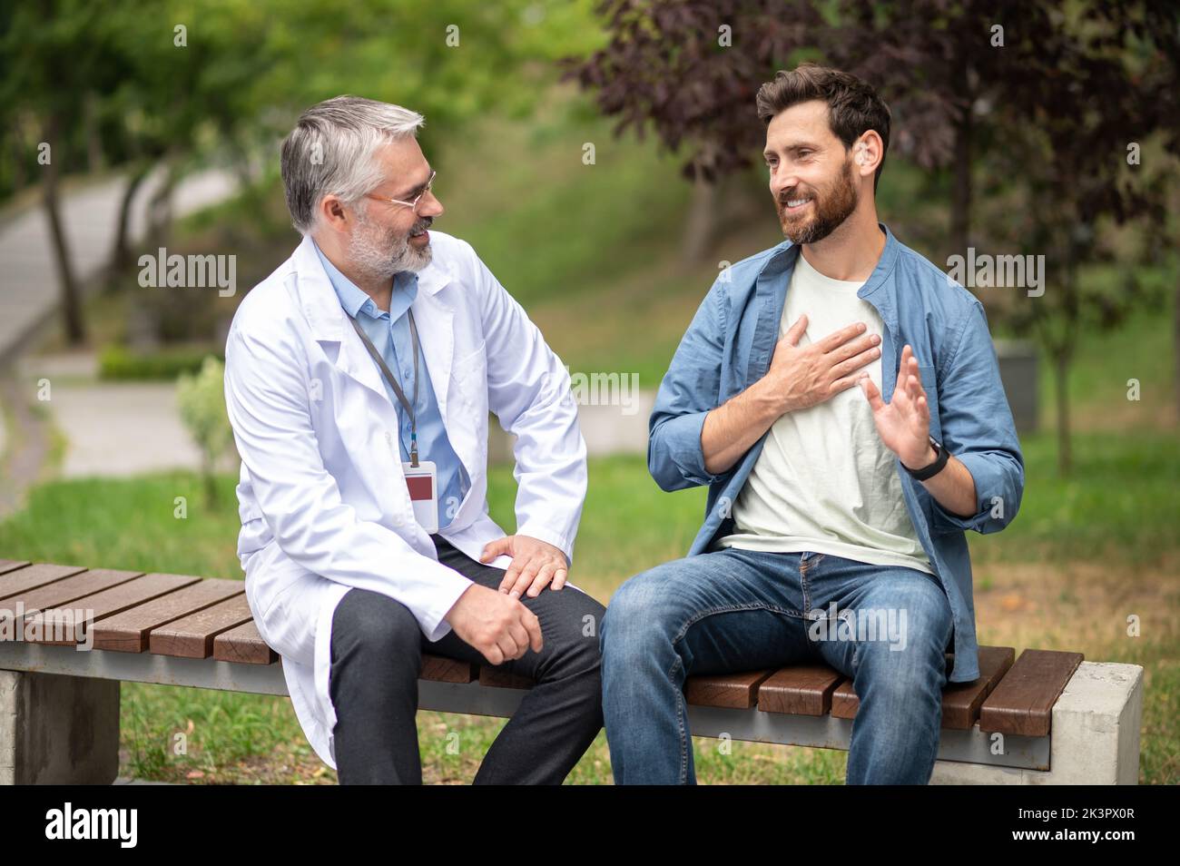 Männlicher Patient, der mit seinem Arzt spricht und über die Symptome berichtet Stockfoto