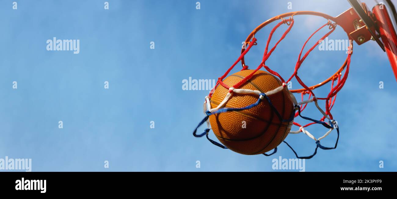 Basketball-Ball erzielte die Punkte vor blauem Himmel Hintergrund auf Outdoor-Streetball-Platz. Banner mit Copy Space Stockfoto