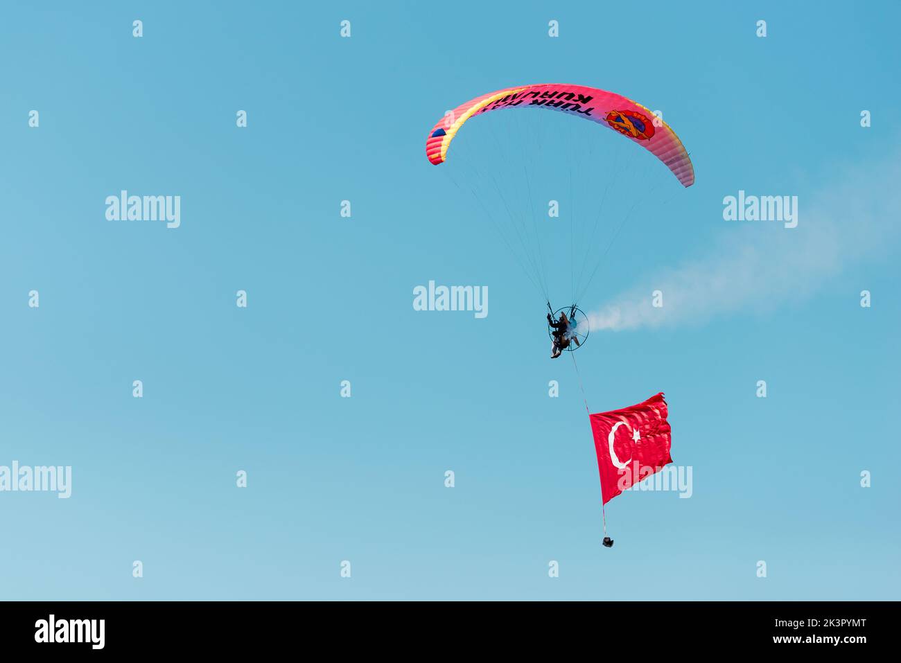 Izmir, Türkei - 9. September 2022: Paramotorspringer am Himmel mit einer riesigen türkischen Flagge am Tag der Freiheit von Izmir in Izmir Konak Türkei Stockfoto